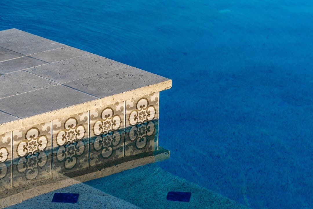 Elegant poolside view featuring intricate tile design and serene blue water.