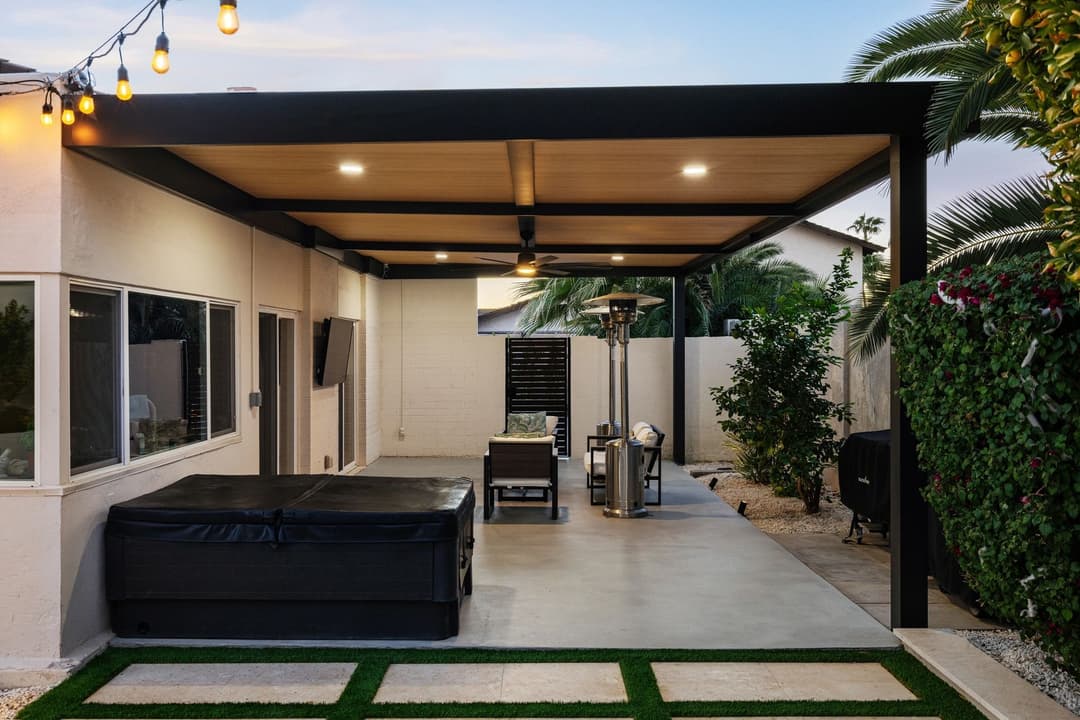 Modern outdoor patio with seating area, hot tub, and ambient lighting in tropical setting.