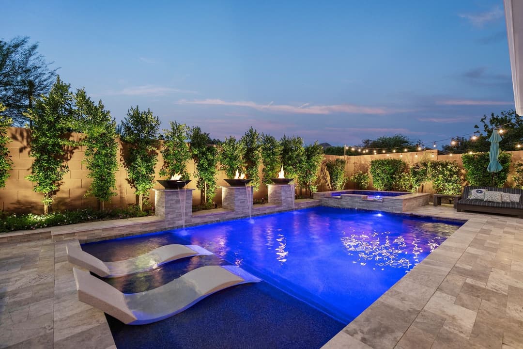 Luxurious backyard pool at dusk with lounge chairs and elegant landscaping.