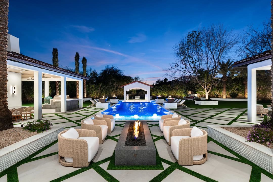 Luxurious outdoor oasis with pool, fire pit, and elegant seating at twilight.