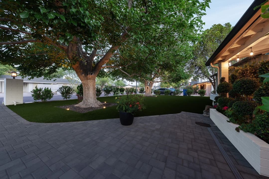 Lush backyard with large trees, well-maintained landscaping, and modern home exterior.