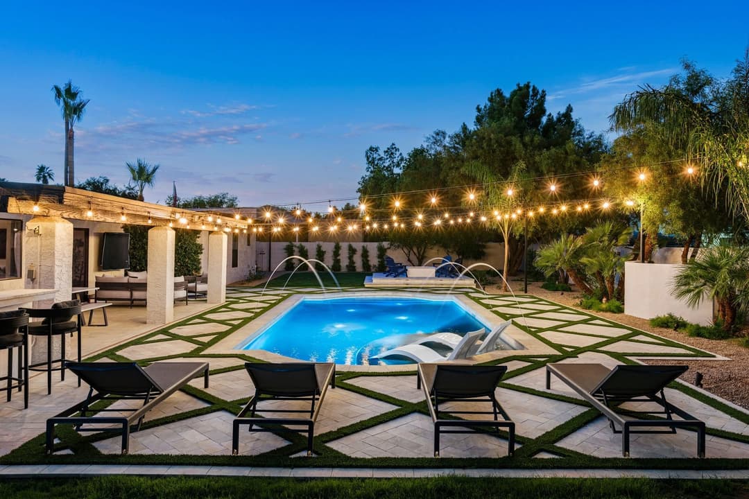 Luxurious backyard with pool, lounge chairs, and string lights at dusk. Perfect for relaxation.