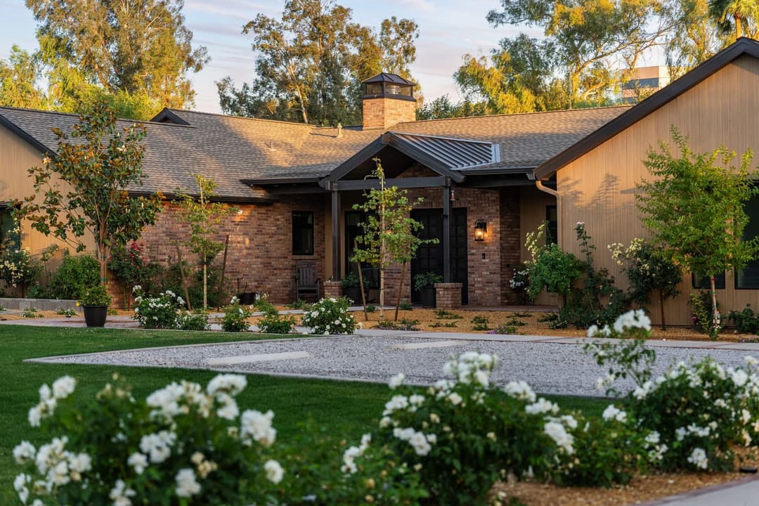 Modern residential home with landscaped front yard and blooming white roses.
