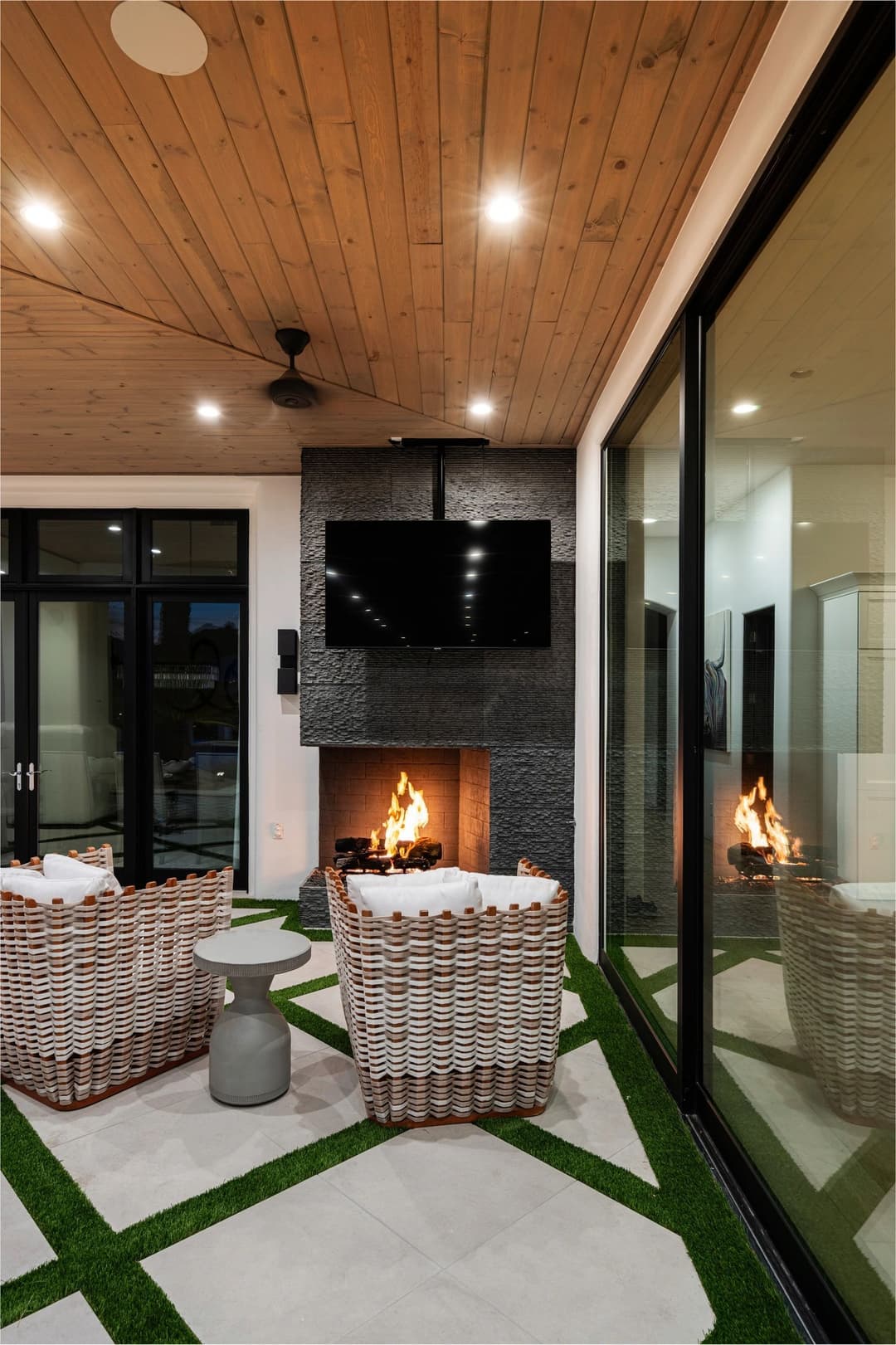 Modern indoor seating area with woven chairs, fireplace, and large windows.