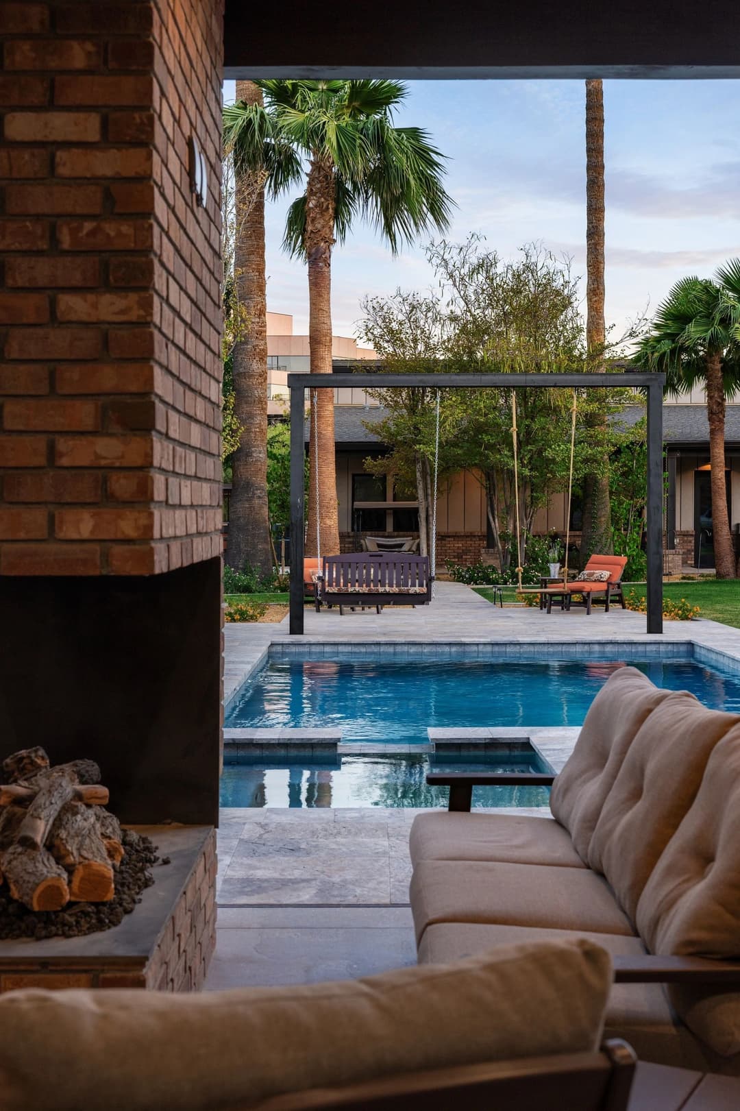 Stylish outdoor seating view overlooking a pool and palm trees in a modern backyard.