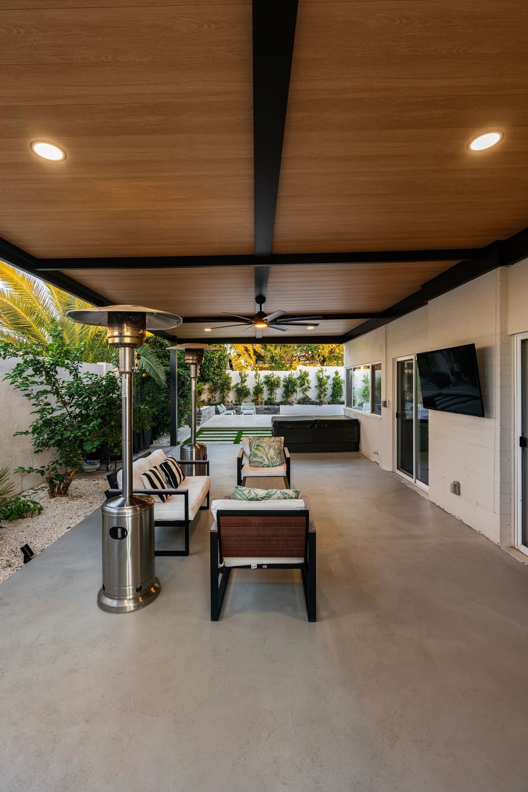 Modern outdoor patio with seating area, heater, and lush greenery for relaxation.